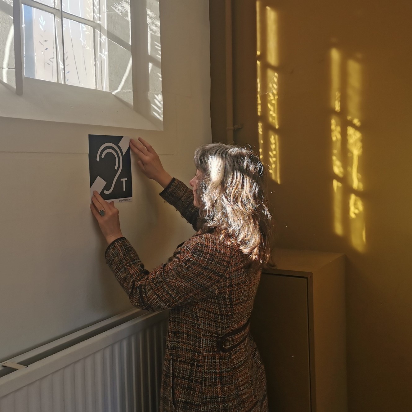 Hearing-loop signage being installed at a worship space &mdash; BS 7594 compliance work by Opus AV